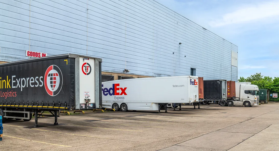 FedEx and TNT Express trailers parked at the loading bay of a distribution warehouse