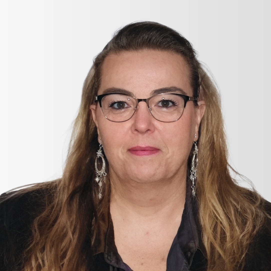 Portrait of Marie-Reine Barth wearing glasses and a dark blouse on a neutral studio background