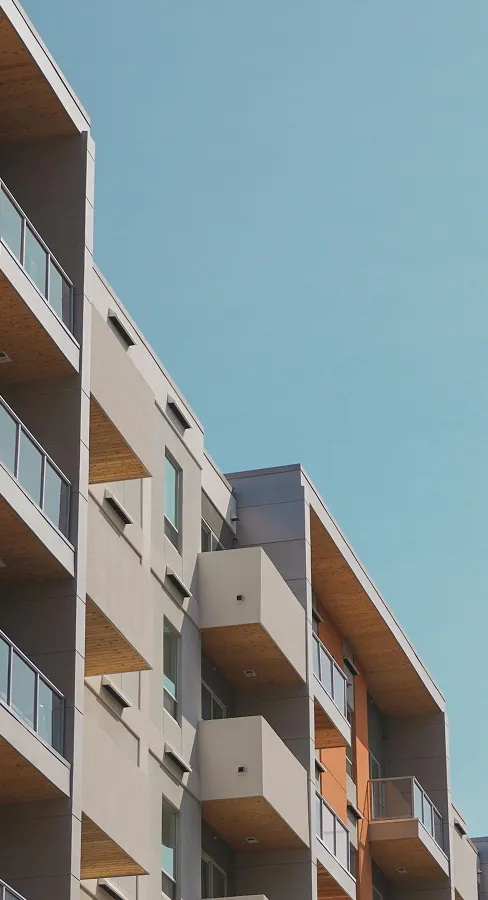 Facade of a modern residential building with wood-clad balconies against a blue sky