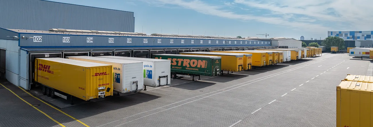 Multi-tenant logistics warehouse with DHL and Lastron trailers at numbered dock doors