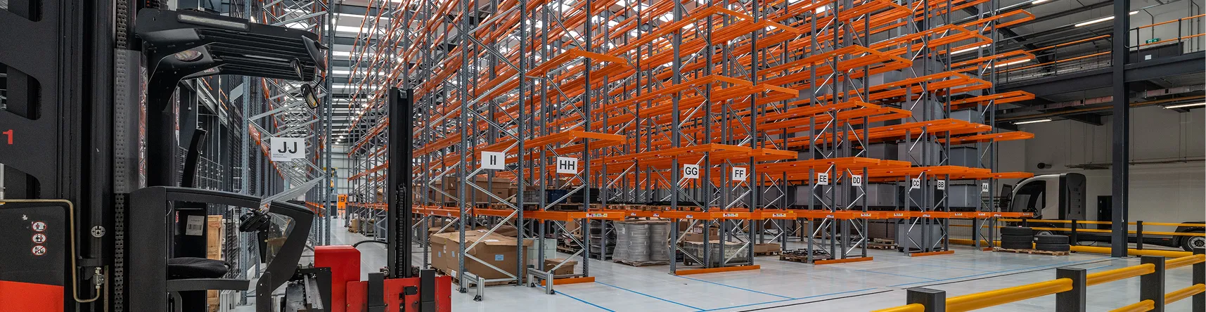 Forklift operating inside a high-bay warehouse with orange pallet racking